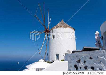 Iconic white windmill with thatched roof on Oia cliff in Santorini Iconic white windmill with thatched roof on Oia cliff in Santorini 141057591