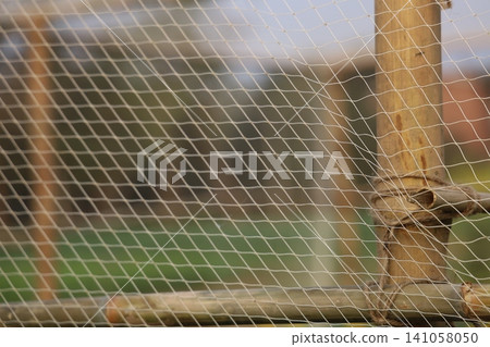 A close-up view of a rusty chicken wire fence with a wooden post A close-up view of a rusty chicken wire fence with a wooden post 141058050