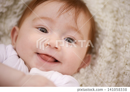 Happy, cute and portrait of baby on blanket playing for child development and positive face. Smile, sweet and closeup of girl kid, infant or newborn relaxing and laying on bed in nursery room at home Happy, cute and portrait of baby on blanket playing for child development and positive face. Smile, sweet and closeup of girl kid, infant or newborn relaxing and laying on bed in nursery room at home 141058338