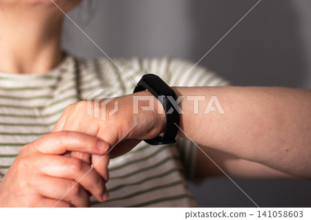 Woman checks health rhythm and pulse then puts watch to sleep. No obsession about data checking. Moving from rigid self-tracking to intuitive balanced tech use Woman checks health rhythm and pulse then puts watch to sleep. No obsession about data checking. Moving from rigid self-tracking to intuitive balanced tech use 141058603