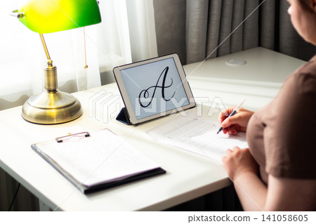 Quiet scene of woman writing with pen. Training accurate handwriting. Therapeutic habit to reduce anxiety and increase clarity. Calmness and digital detox 141058605