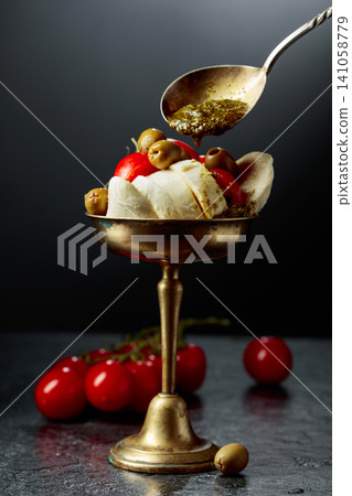 Mozzarella with pesto sauce, green olives, and red cherry tomatoes. Mozzarella with pesto sauce, green olives, and red cherry tomatoes. 141058779