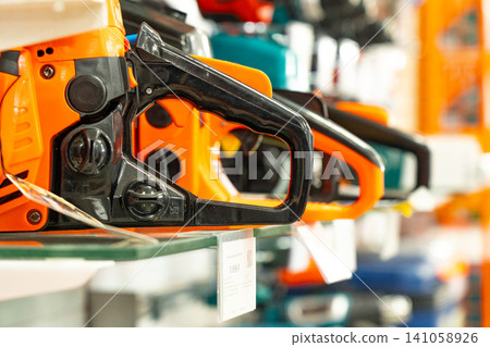 A Variety of Electric Chainsaws Displayed on Shelves in a Tool Store, Showcasing Their Unique Designs and Features for Wood Cutting Enthusiasts and Professionals A Variety of Electric Chainsaws Displayed on Shelves in a Tool Store, Showcasing Their Unique Designs and Features for Wood Cutting Enthusiasts and Professionals 141058926