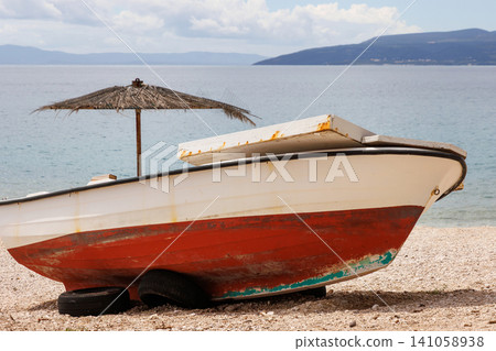 Painted boat resting on a pebble beach beside the Adriatic Sea in Makarska, Croatia. Painted boat resting on a pebble beach beside the Adriatic Sea in Makarska, Croatia. 141058938
