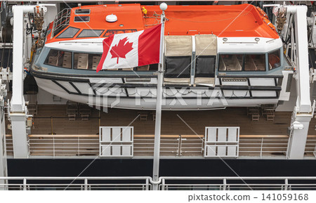 Orange Lifeboat on Cruise Ship Deck and Canadian flag. Lifeboats displayed aboard on a cruise ship, for safety and preparedness measures Orange Lifeboat on Cruise Ship Deck and Canadian flag. Lifeboats displayed aboard on a cruise ship, for safety and preparedness measures 141059168