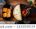 Indian Chicken Curry with Roti Flatbread and Toasted Bread on Wooden Table 141059539