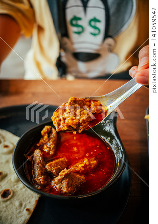 Indian Chicken Curry with Roti Flatbread and Toasted Bread on Wooden Table 141059542