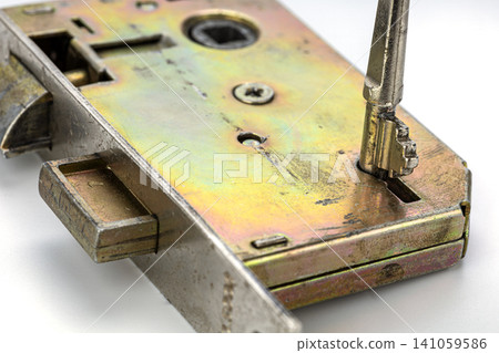 Vintage Brass Mortise Door Lock Mechanism with Antique Skeleton Key Inserted in Keyhole Showing Detailed Metallic Surface Texture, Bolt, Screws and Internal Locking Components in Macro Photography Vintage Brass Mortise Door Lock Mechanism with Antique Skeleton Key Inserted in Keyhole Showing Detailed Metallic Surface Texture, Bolt, Screws and Internal Locking Components in Macro Photography 141059586