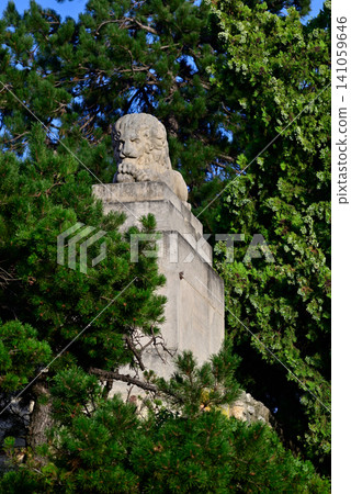 Stone lion statue among green trees Stone lion statue among green trees 141059646