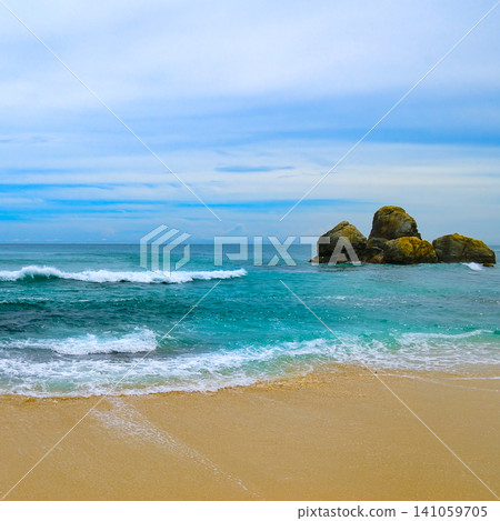 Beautiful tropical beach with turquoise water and scenic rock formation. Turquoise ocean waves crashing on golden sand under a blue cloudy sky. Beautiful tropical beach with turquoise water and scenic rock formation. Turquoise ocean waves crashing on golden sand under a blue cloudy sky. 141059705