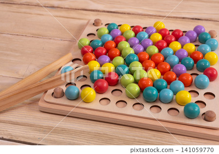 Educational wooden toy lies on desk. Colorful round ball elements help children develop fine motor skills. Eco friendly learning material provides fun intellectual activity for toddlers. Educational wooden toy lies on desk. Colorful round ball elements help children develop fine motor skills. Eco friendly learning material provides fun intellectual activity for toddlers. 141059770