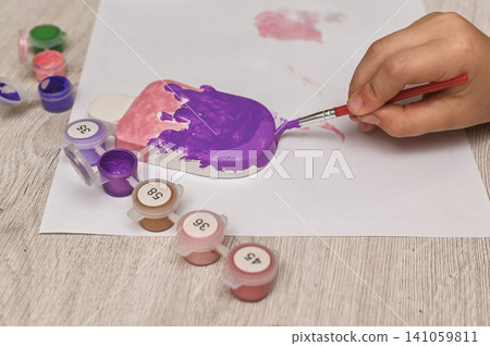 Close up hand painting plaster ice cream figurine with purple gouache. Close up hand painting plaster ice cream figurine with purple gouache. 141059811