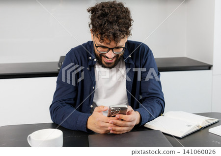 Young man smiling using smartphone at home Young man smiling using smartphone at home 141060026