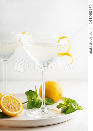Refreshing lemon cocktail in martini glass with mint garnish 141060172