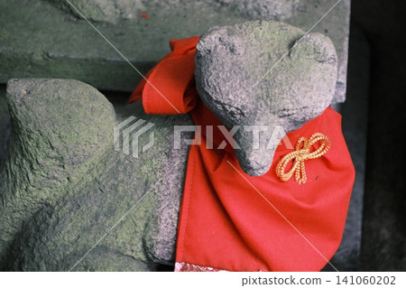 一尊長滿青苔的石雕狐狸雕像,狐狸穿著紅色圍裙 一尊長滿青苔的石雕狐狸雕像,狐狸穿著紅色圍裙 141060202
