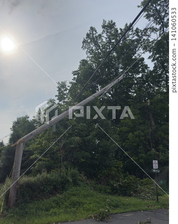 A utility pole broken by the storm and power lines hanging down: the scene of damage to essential infrastructure. A utility pole broken by the storm and power lines hanging down: the scene of damage to essential infrastructure. 141060533