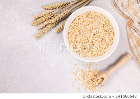 Oat flakes in bowl with wheat ears and scoop Oat flakes in bowl with wheat ears and scoop 141060648