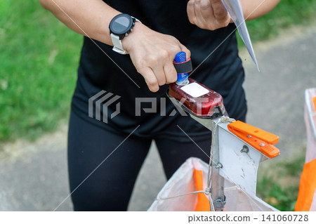 an orienteering athlete using an electronic timing punch an orienteering athlete using an electronic timing punch 141060728