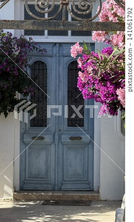 Blue Door Framed by Colorful Bougainvillea Flowers Blue Door Framed by Colorful Bougainvillea Flowers 141061792