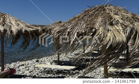 Beach Sun Loungers Under Straw Umbrellas by the Sea Beach Sun Loungers Under Straw Umbrellas by the Sea 141061799