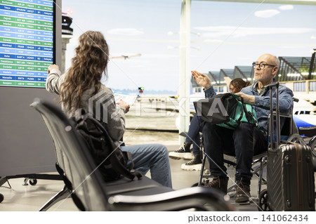 Senior man using wheelchair and woman supporting him with luggage and boarding pass. Elderly retirees embracing accessible tourism, inclusion and freedom, barrier-free travel during retirement. Senior man using wheelchair and woman supporting him with luggage and boarding pass. Elderly retirees embracing accessible tourism, inclusion and freedom, barrier-free travel during retirement. 141062434