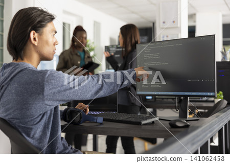 Asian male programmer points at desktop monitor with surprised expression after identifying key code statement to solve web development issue. Man reviews HTML scripts in modern tech workspace. Asian male programmer points at desktop monitor with surprised expression after identifying key code statement to solve web development issue. Man reviews HTML scripts in modern tech workspace. 141062458