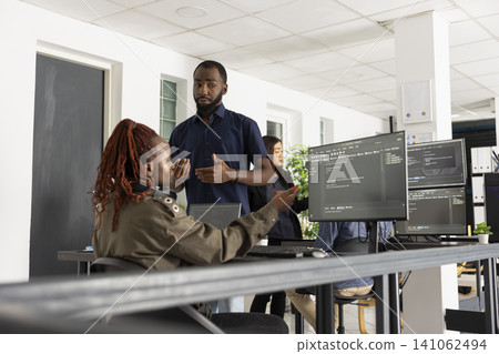African American developers work together in startup office, comparing website code on desktop pc. Focused programmers discuss strategy, technology and collaborative digital problem solving. African American developers work together in startup office, comparing website code on desktop pc. Focused programmers discuss strategy, technology and collaborative digital problem solving. 141062494
