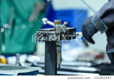 Disassembled common rail diesel fuel injector fixed in metal vice clamp on workbench during repair in workshop Disassembled common rail diesel fuel injector fixed in metal vice clamp on workbench during repair in workshop 141062847
