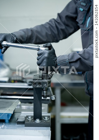 Mechanic hand in glove tightening common rail diesel fuel injector with torque wrench tool on metal clamp holder in workshop Mechanic hand in glove tightening common rail diesel fuel injector with torque wrench tool on metal clamp holder in workshop 141062854