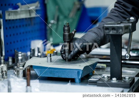 Mechanic hand checking common rail diesel fuel injector nozzle for contamination on clean surface during repair process in workshop Mechanic hand checking common rail diesel fuel injector nozzle for contamination on clean surface during repair process in workshop 141062855