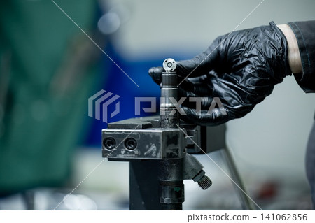 Mechanic hand installing shim spacer gasket washer onto common rail diesel fuel injector internal part during repair workshop Mechanic hand installing shim spacer gasket washer onto common rail diesel fuel injector internal part during repair workshop 141062856