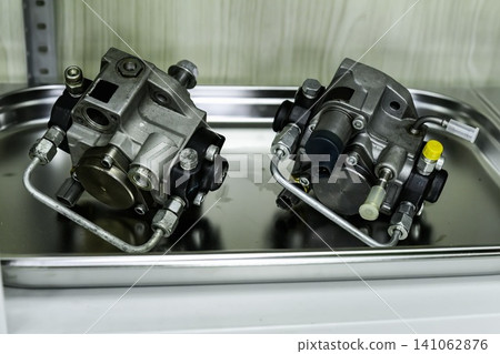 Two common rail high pressure diesel fuel pumps on metal tray on shelf during diagnostics and repair in workshop Two common rail high pressure diesel fuel pumps on metal tray on shelf during diagnostics and repair in workshop 141062876