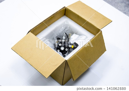 High pressure common rail diesel fuel pump packed in open cardboard box with test report for shipping on white background High pressure common rail diesel fuel pump packed in open cardboard box with test report for shipping on white background 141062880