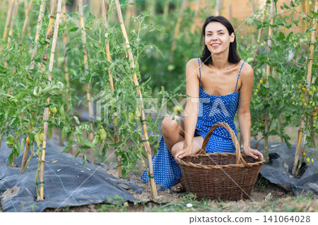 Adult woman with basket in cottage garden 141064028