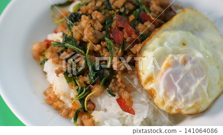 stir fried pork with holy basil on top with fried egg on cooked rice stir fried pork with holy basil on top with fried egg on cooked rice 141064086