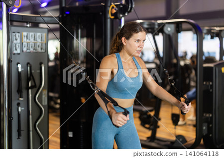 Woman doing exercises for chest muscles in crossover Woman doing exercises for chest muscles in crossover 141064118
