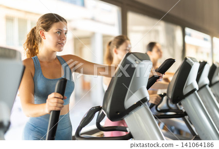 Woman training on elliptical machine Woman training on elliptical machine 141064186
