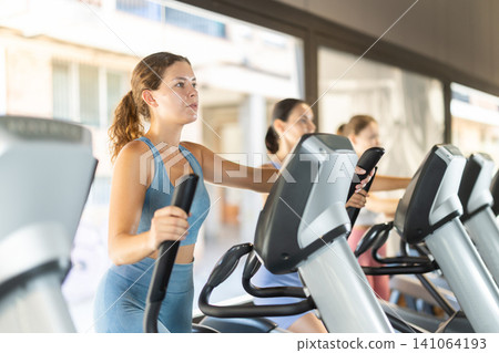 Woman training on elliptical machine Woman training on elliptical machine 141064193