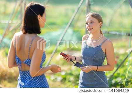 Two positive peasant girls are chatting in garden Two positive peasant girls are chatting in garden 141064209