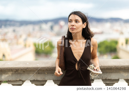 Woman walks through historical center of Barcelona with phone Woman walks through historical center of Barcelona with phone 141064298