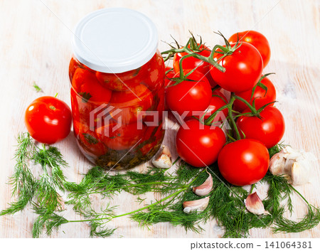 Jar with pickled tomatoes, dill, garlic and ripe tomatoes on the table Jar with pickled tomatoes, dill, garlic and ripe tomatoes on the table 141064381