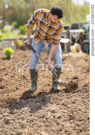Young man with shovel working on farm field Young man with shovel working on farm field 141064382