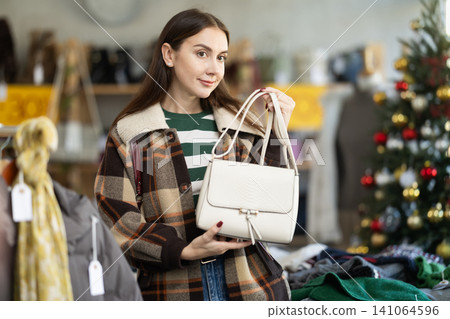 Young woman choosing handbag in clothing store Young woman choosing handbag in clothing store 141064596