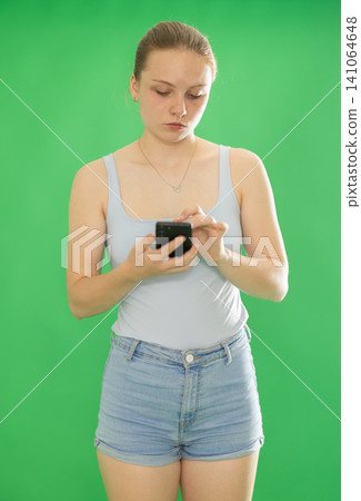 Teenage girl in blue top looks at information on smartphone screen. Chroma key compositing Teenage girl in blue top looks at information on smartphone screen. Chroma key compositing 141064648