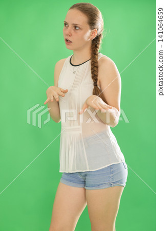Teenage girl explaining or telling something in front of green screen 141064659