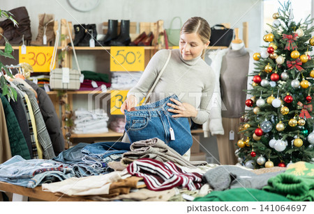 Adult woman choosing jeans in clothing store Adult woman choosing jeans in clothing store 141064697