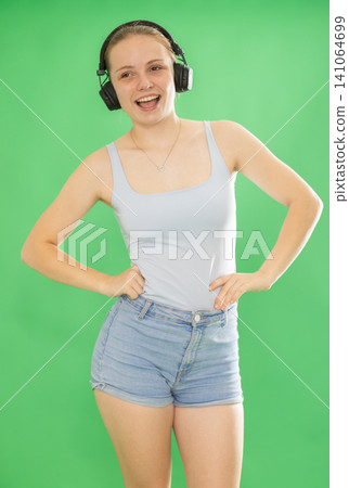 Teenage girl listening to music and dancing in front of green screen Teenage girl listening to music and dancing in front of green screen 141064699