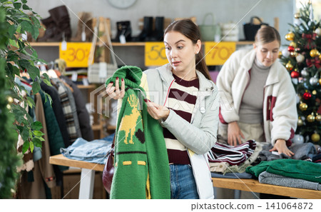 Woman client looks at products in store, choose closely warm sweater Woman client looks at products in store, choose closely warm sweater 141064872