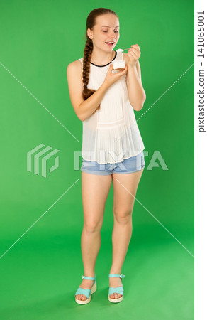 Girl in white blouse eats yogurt. Chroma key compositing Girl in white blouse eats yogurt. Chroma key compositing 141065001