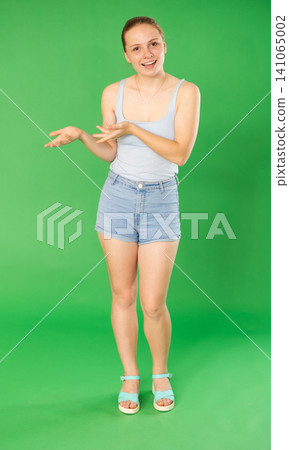 Teenage girl explaining or telling something in front of green screen Teenage girl explaining or telling something in front of green screen 141065002